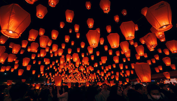 "A bustling scene of a lantern festival at night, with hundreds of glowing paper lanterns ascending into the dark sky. Their warm orange light creates a magical and celebratory ambiance."