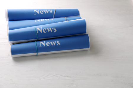 Rolls of paper with words news on wooden table