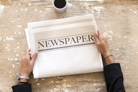 Woman reading newspaper on wooden background