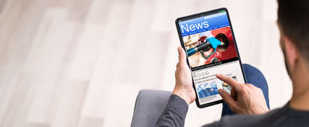 Reading newspaper article online on digital tablet Stock Photo