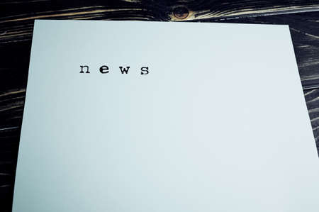 The word news stamped on a paper lying on wooden surface with copy space