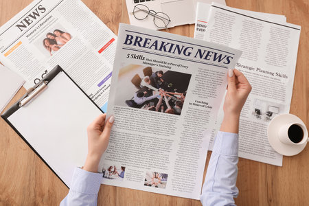 Young woman reading newspaper at table Stock Photo