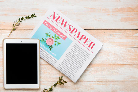 Composition with newspaper and tablet computer on light wooden background