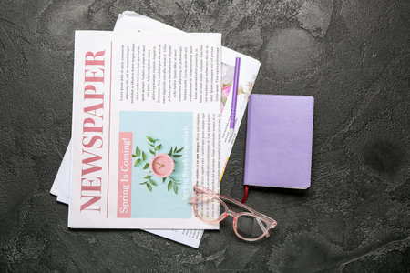 Newspapers with eyeglasses notebook and pen on dark background Stock Photo