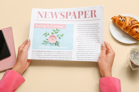 Woman reading newspaper on beige background closeup