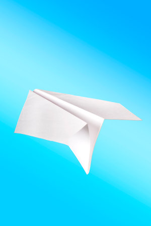 Airplane toy made of white paper on blue background close up