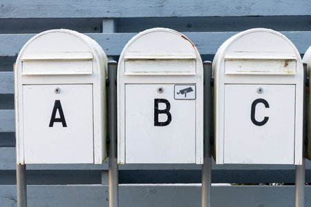 Outdoor mailboxes placed along the street between neighboring residential houses metal post boxes used for daily postal delivery in a suburban area Stock Photo