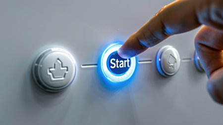 Close up view of a person s finger pressing an illuminated start button on a modern control panel symbolizing technology and machine activation