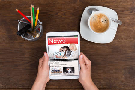 Close up of person hands holding mobile phone showing news at desk