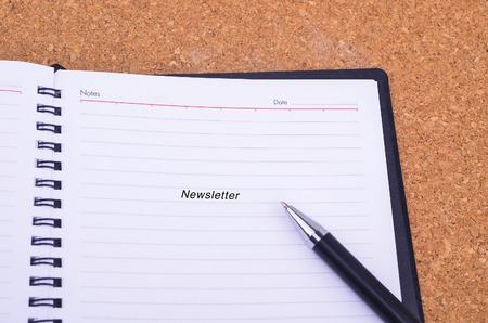 A pen and notebook written newsletter on a wooden table with copyspace area