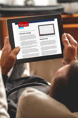 Senior reading news on tablet looking information