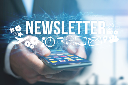 Concept view of man holding futuristic interface with newsletter title and multimedia icons flying all around internet concept