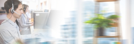 Digital composite of customer service assistants with headsets with bright background